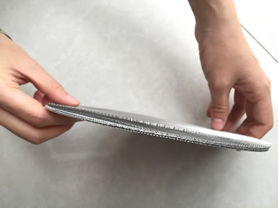 Several pieces of round woven wire mesh filters are held by two hands.