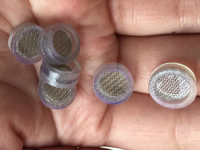 A hand is holding some small filter discs with translucent edges.